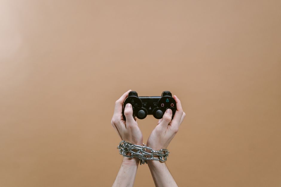 Mãos encadeadas segurando um controle de videogame, simbolizando dependência ou restrição em um contexto de entretenimento digital.