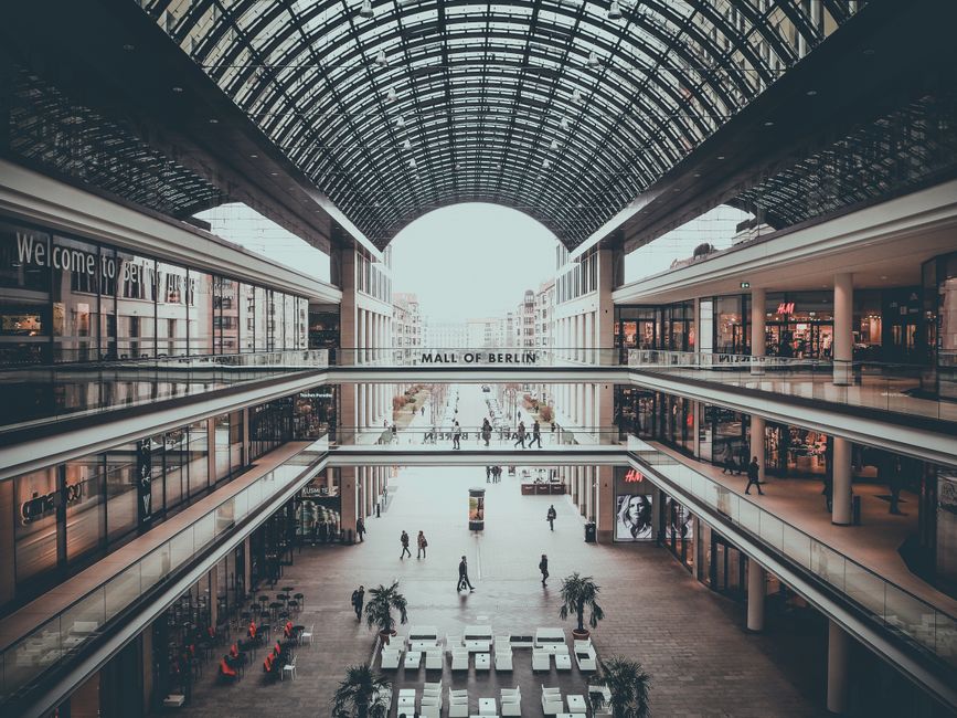 Interior moderno de um shopping center com espaço aberto, iluminação natural e fluxo de pessoas para ilustrar tema de comércio e comércio varejista.