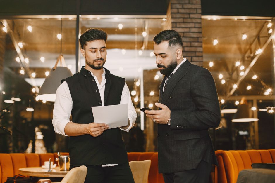 Dois homens em uma conversa profissional em um ambiente contemporâneo, destacando networking e relacionamento empresarial.