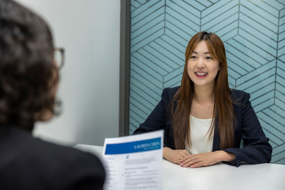 Mulher em uma entrevista de emprego, sorrindo e demonstrando confiança em um ambiente profissional.