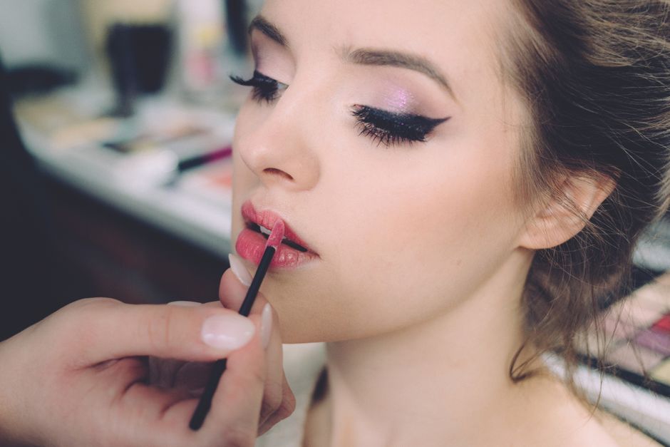 Mulher sendo maquiada para um evento ou sessão de fotos, destacando a preparação de beleza.