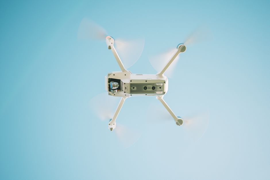 Dronóvel em voo contra um céu azul, representando inovação tecnológica e entregas automatizadas.