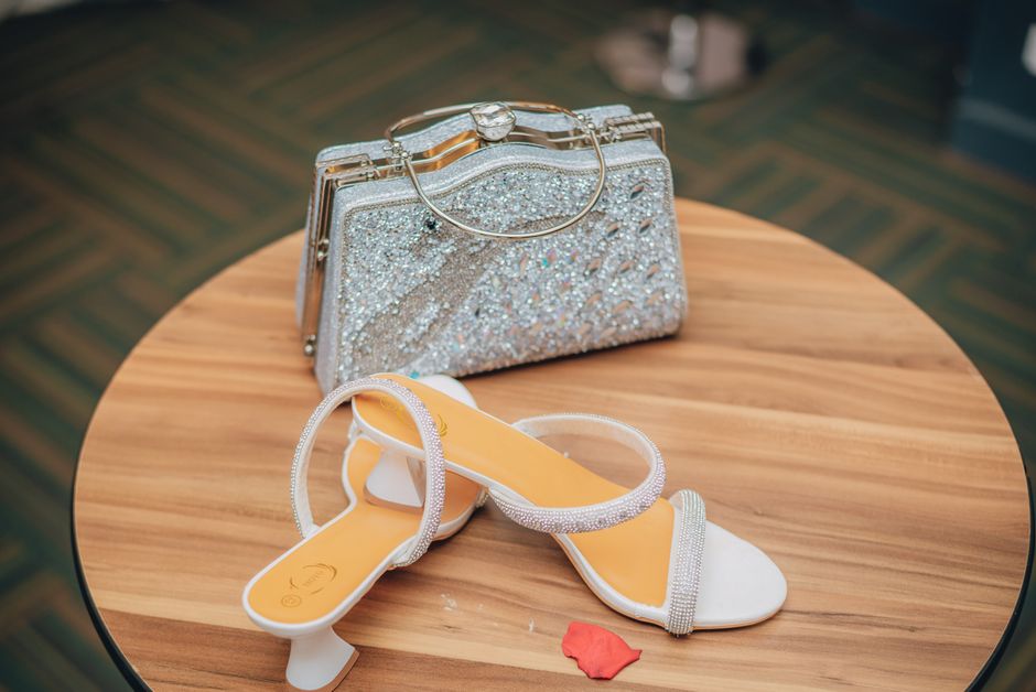 Imagem de uma bolsa de festas decorada com pedras brilhantes e um par de sandálias de salto allegro com detalhes em pedraria, ideal para um artigo sobre moda e acessórios para eventos.