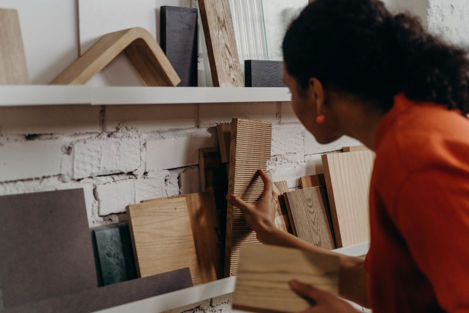 Mulher escolhendo acabamentos de madeira em loja de materiais de construção, representando seleção de materiais para projetos de decoração ou construção.