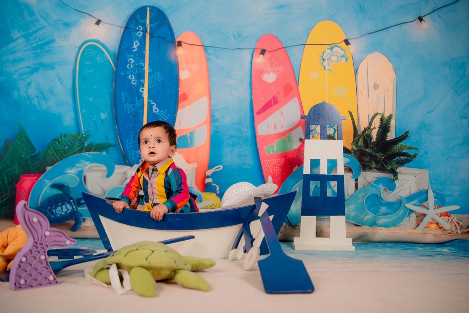Criança em ambiente decorado com tema de surf e praia, ideal para fotos de infância ou celebrações ao ar livre.