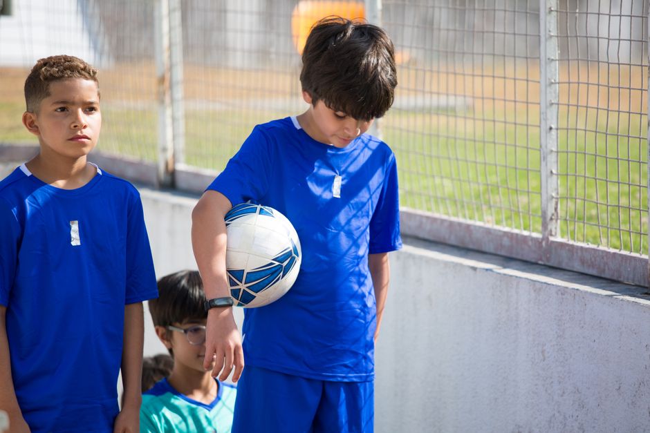 Jovens atletas de futebol em treinamento ou jogo ao ar livre, destacando preparação esportiva infantil.