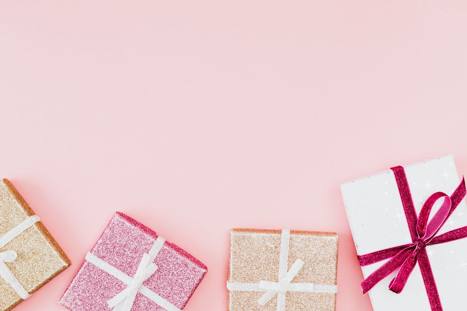 Caixas de presentes decoradas com fitas em um fundo rosa, simbolizando celebrações e momentos especiais.