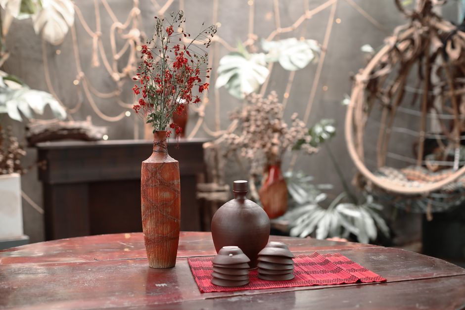Imagem de um ambiente com estética rústica e natural, decorado com vasos de cerâmica e vasos com plantas secas, transmitindo uma atmosfera aconchegante e orgânica.