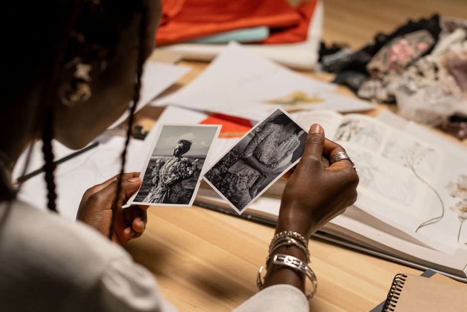 Pessoa analisando fotos antigas enquanto trabalha em um projeto criativo ou artístico.
