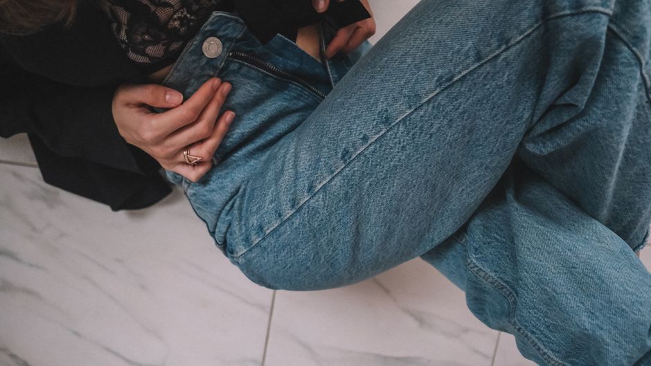 Imagem de uma pessoa casualmente sentada, com foco no estilo de vestimenta e na postura relaxada, ilustrando temas de moda ou estilo de vida descontraído.
