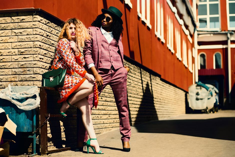 Duas mulheres com estilo fashion sofisticado posando na rua, destacando moda urbana e diversidade cultural.