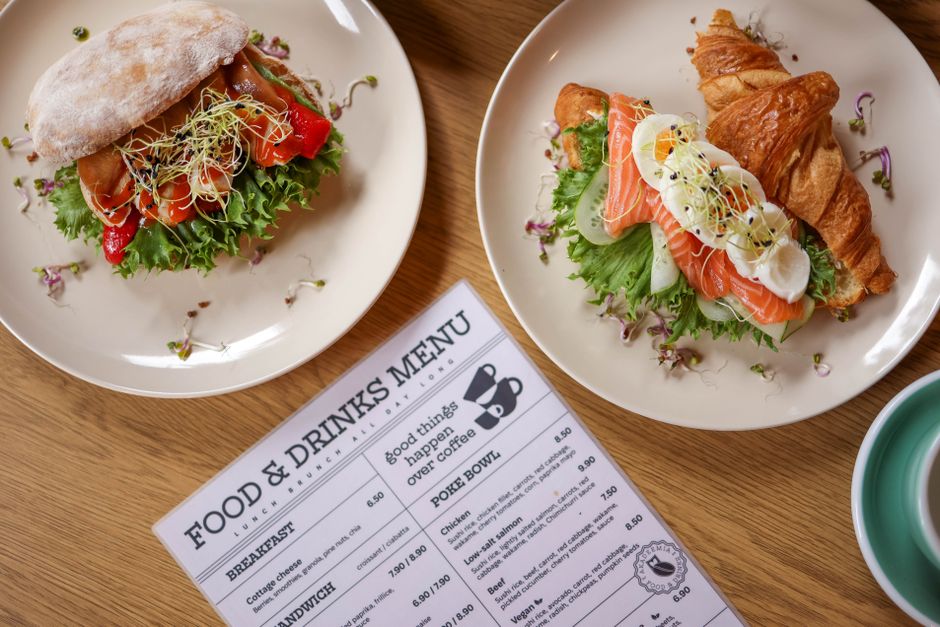 Dupla de opções de café da manhã com sanduíche e ovos, acompanhadas de cartão de menu, típicas para um café em um restaurante ou padaria artesanal.