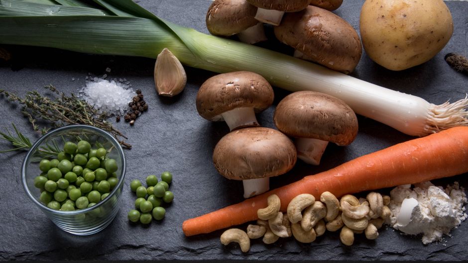 Imagem de ingredientes frescos e variados de origem vegetal dispostos sobre uma superfície escura, ideal para um artigo sobre alimentação saudável ou culinária natural.