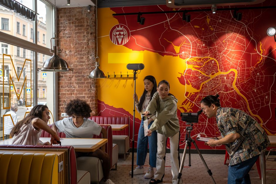 Cena de gravação de conteúdo audiovisual, com equipe profissional filmando em um ambiente urbano decorado de forma moderna.