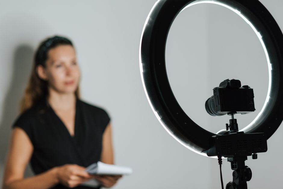 Mulher realizando uma gravação de vídeo com luz de anel em um ambiente de estúdio, ideal para conteúdo digital ou vídeos de apresentação.
