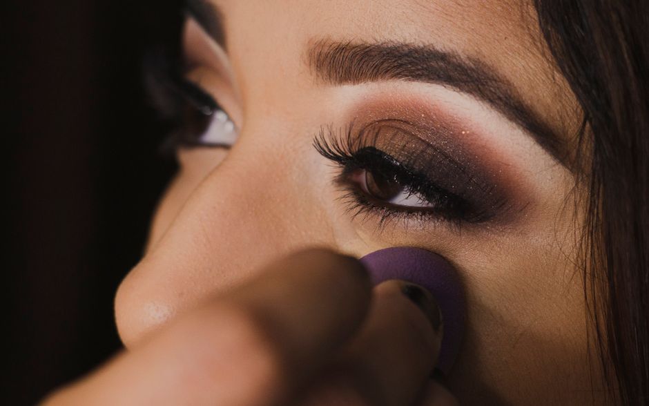 Imagem de uma mulher sendo maquiada, focada na preparação do rosto para destaque na beleza e maquiagem profissional.