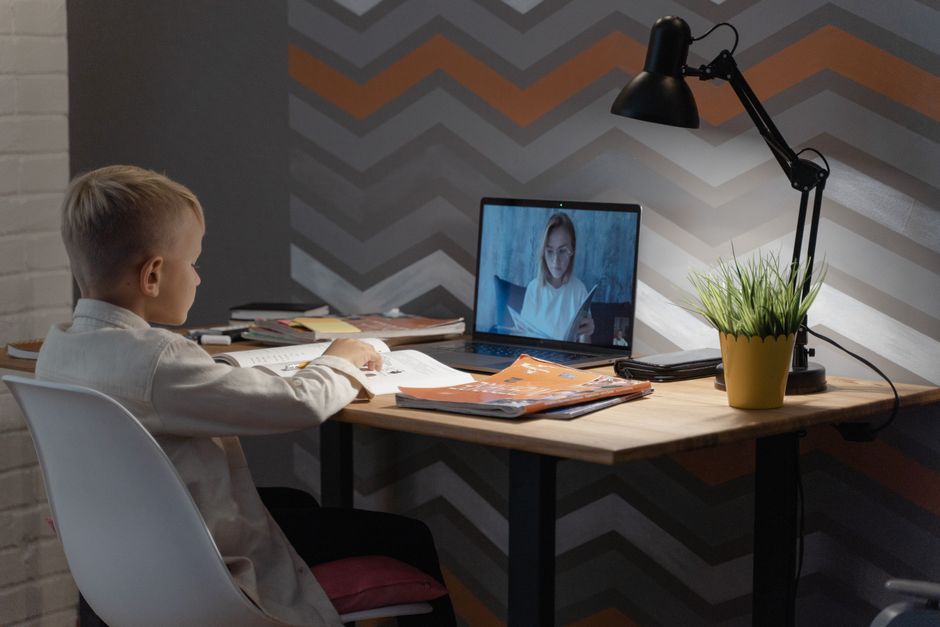 Criança estudando em casa com aulas virtuais, reforçando o tema de educação e tecnologia.