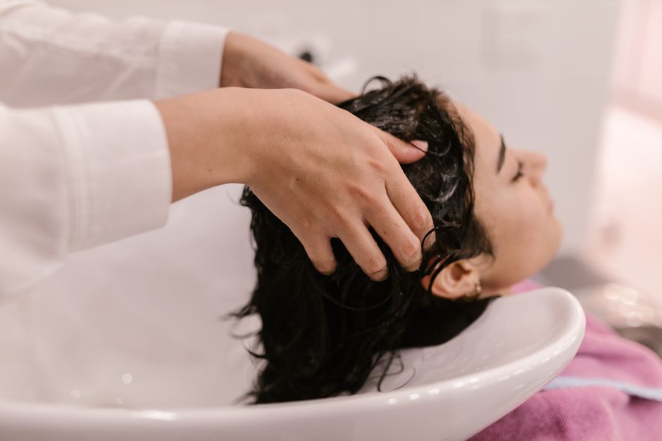 Pessoa recebendo tratamento de lavagem capilar ou cuidados com os cabelos em um salão de beleza.