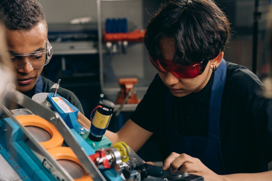 Jovens trabalhando em um projeto de engenharia ou tecnologia em um laboratório ou oficina.
