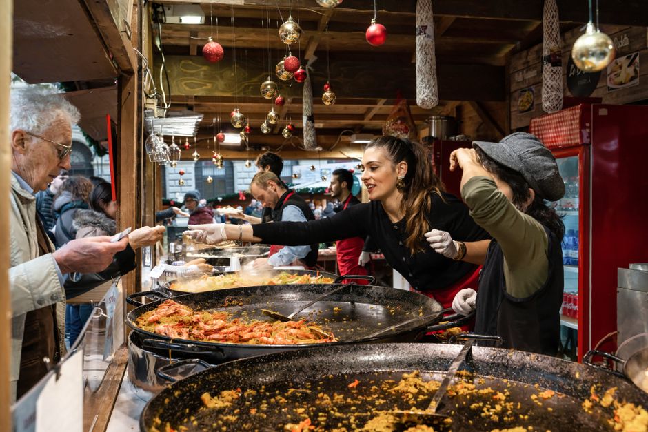 Vendedora atendendo clientes em um food truck com ambiente natalino, oferecendo comida em um evento ao ar livre.