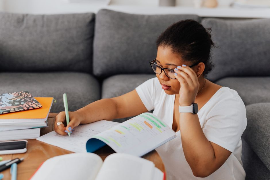 Mulher estudando e organizando anotações em ambiente de descanso, transmitindo foco nos estudos e produtividade.