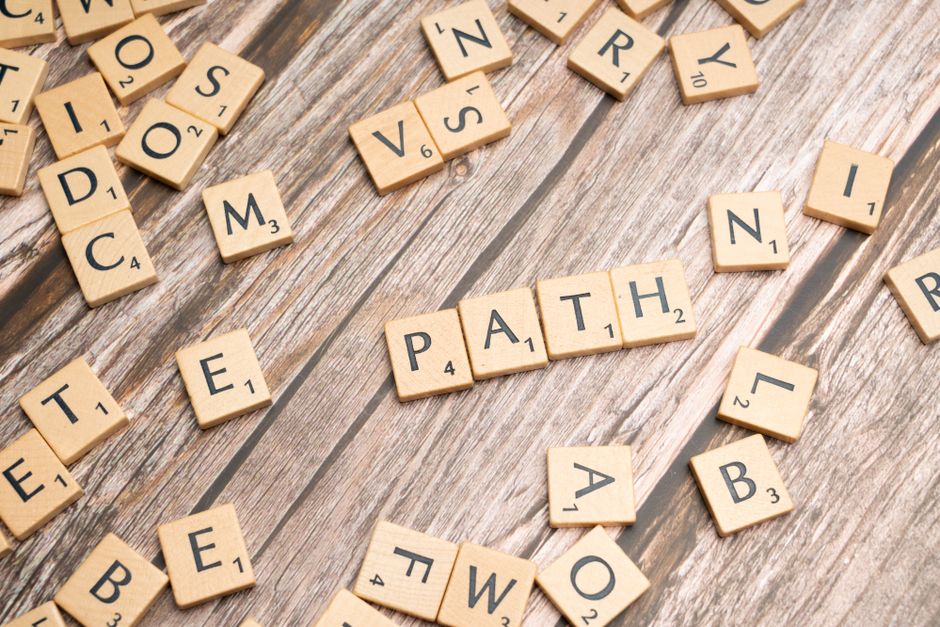 Imagem de peças de dominó com uma peça central destacando a palavra 'PATH', representando escolhas e trajetórias na carreira ou vida pessoal.