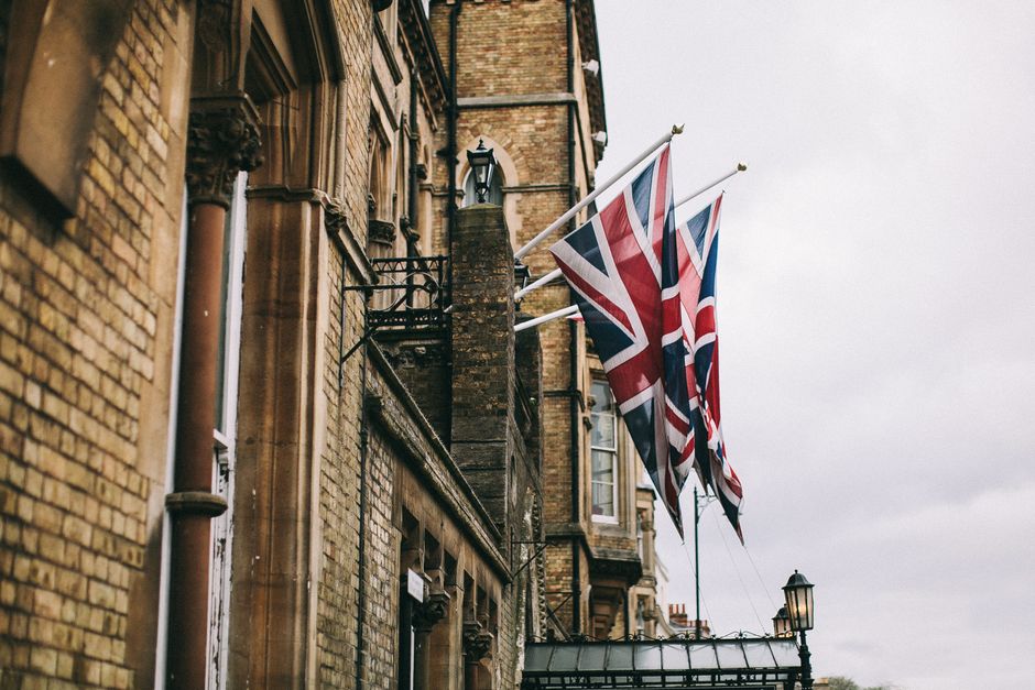 Bandeiras do Reino Unido destacadas em um edifício histórico na cidade, simbolizando patriotismo ou eventos culturais britânicos.