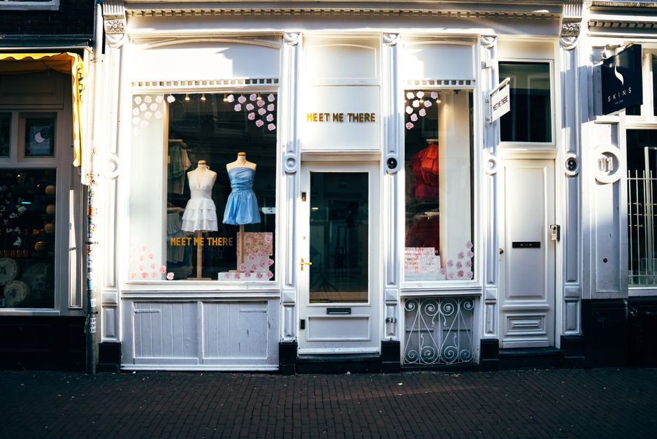 Fachada de loja de roupas femininas com manequins exibindo vestidos na vitrine, convidando para uma experiência de compra diferenciada.