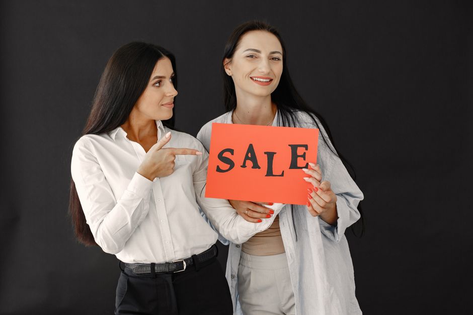 Duas mulheres comemorando uma promoção de vendas em um ambiente de negócios, destacando entusiasmo e sucesso em estratégias de marketing.