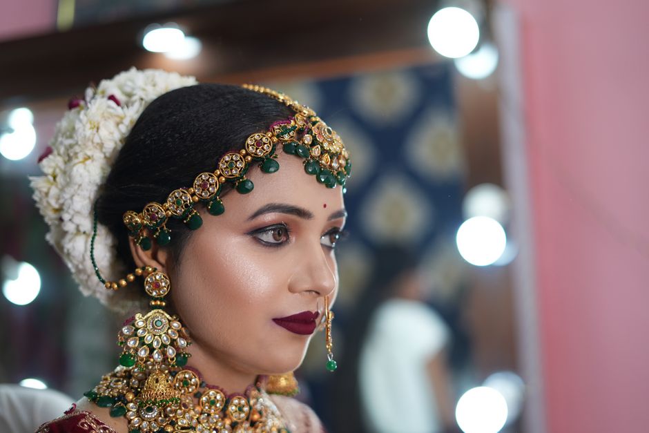 Mulher vestida com trajes tradicionais e joias elaboradas, pronta para uma cerimônia cultural ou casamento na Índia.