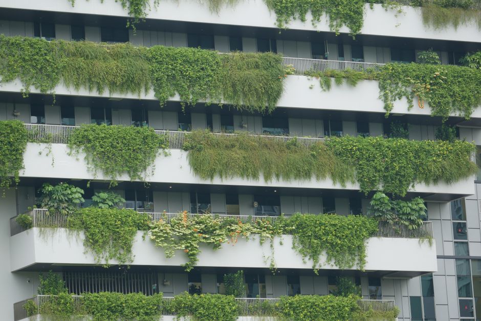 Edifício residencial com varandas verdes e plantas que criam um aspecto sustentável e ecológico na arquitetura urbana.