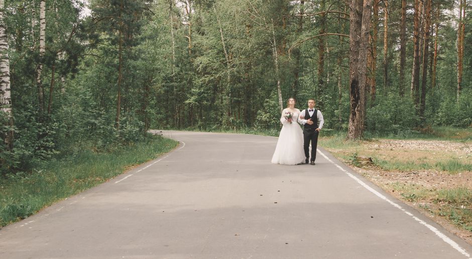 Casal de noivos caminhando juntos pela estrada em meio à natureza, simbolizando o começo de uma nova etapa na vida a dois.