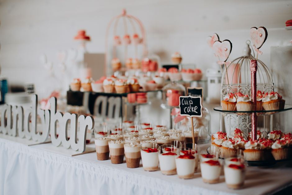 Mesa decorada com doces e cupcakes em tema de casamento, ideal para ilustrar comemorações especiais e festas temáticas.