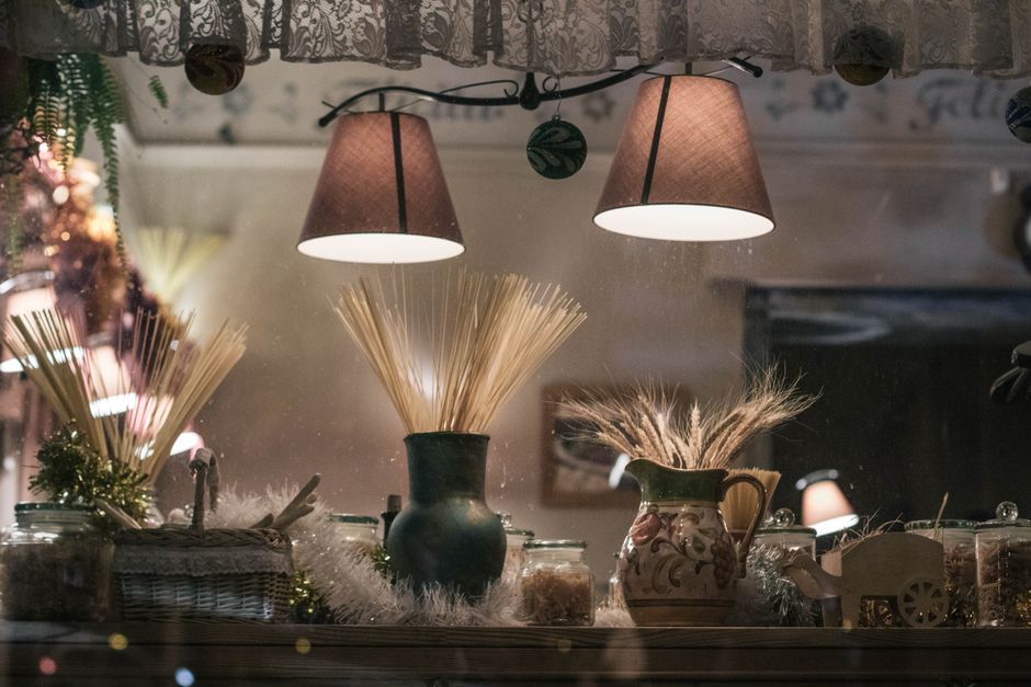 Decoração de Natal na janela com vasos decorativos, luzes e elementos tradicionais em clima festivo.