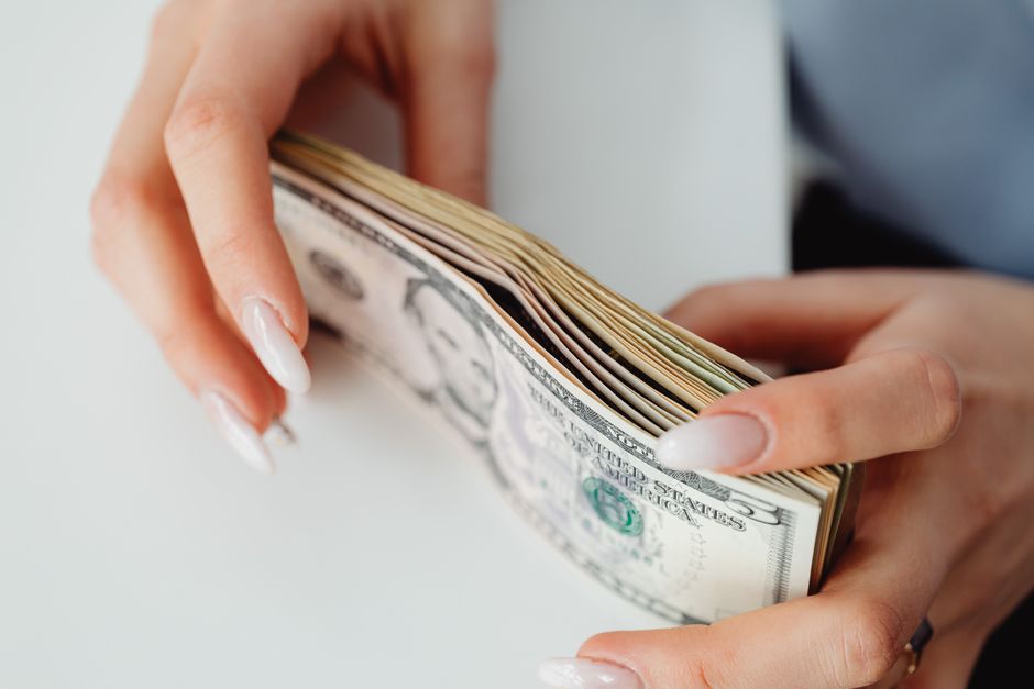 Imagem de mãos segurando uma pilha de dinheiro, simbolizando temas de finanças e investimentos.