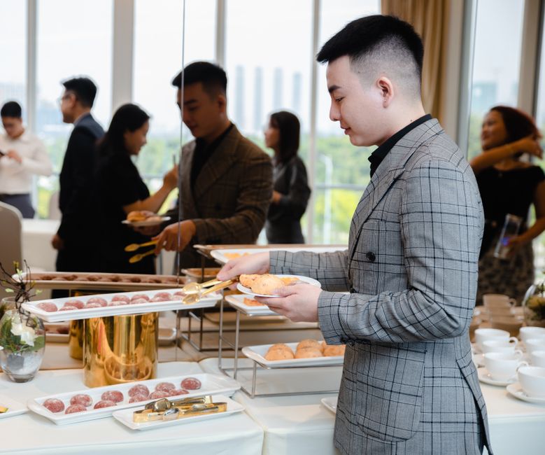 Homem escolhendo comida em um evento de networking ou reunião de negócios, destacando a importância de eventos corporativos.