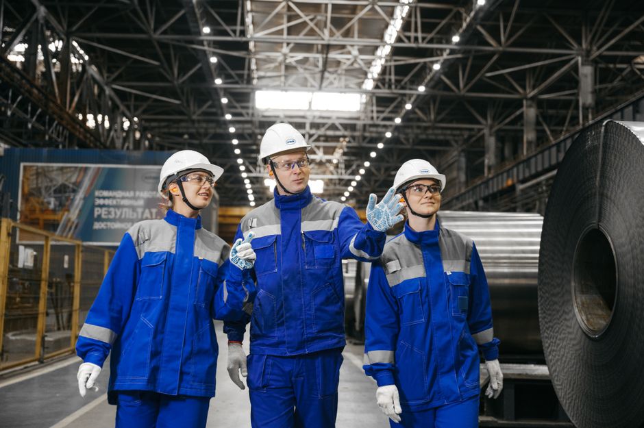Três engenheiros industriais avaliando processos de produção em uma fábrica de grande porte.