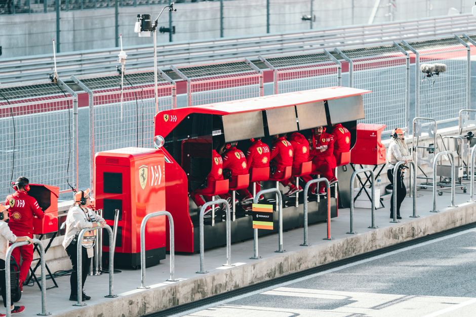 Equipe de Fórmula 1 aguardando na área de box, destacando a preparação e estratégia na corrida.