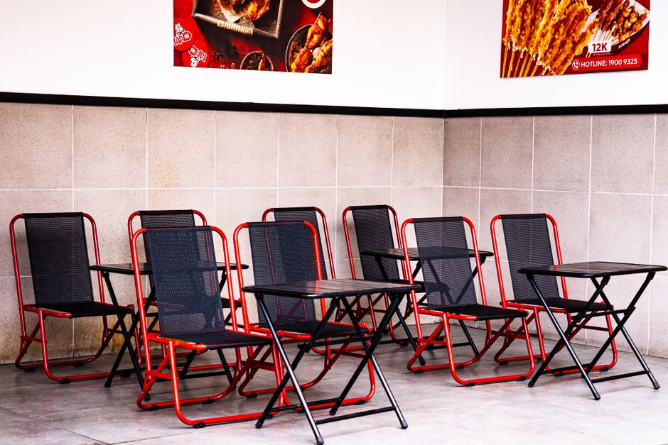 Imagem de uma área de lounge ou fila de espera com cadeiras e mesas, geralmente usada em ambientes comerciais ou de atendimento ao público.