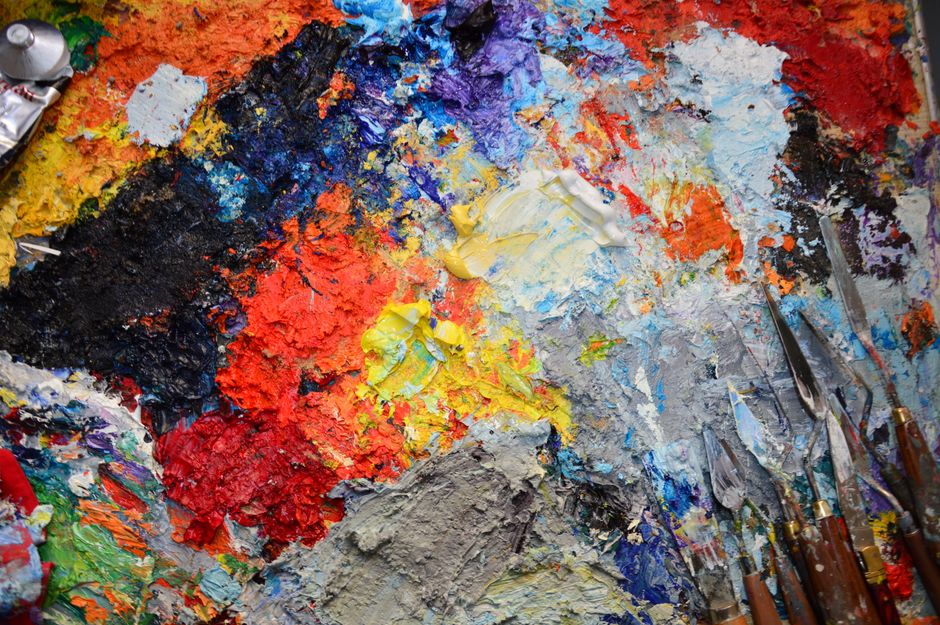 Paleta de cores vibrantes e pincéis utilizados por um artista, representando criatividade e expressão artística.