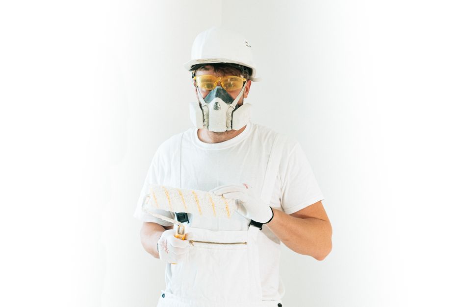 Profissional de construção civil usando equipamentos de proteção enquanto trabalha em um projeto de manutenção ou construção.