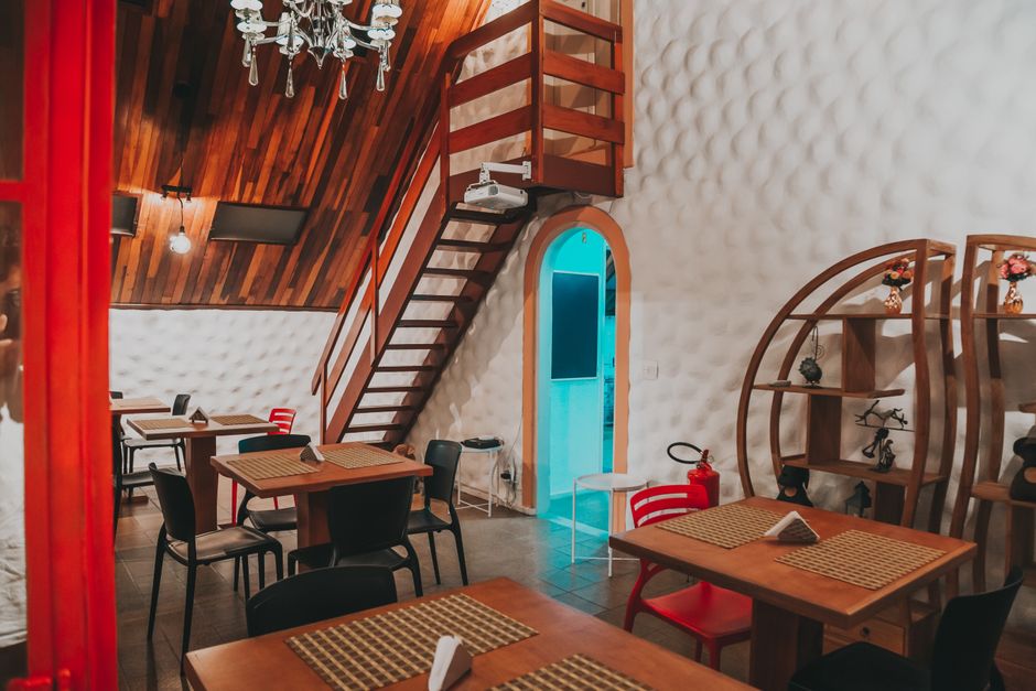 Interior de restaurante aconchegante com iluminação amarelada, decoração moderna e mesas preparadas para os clientes.