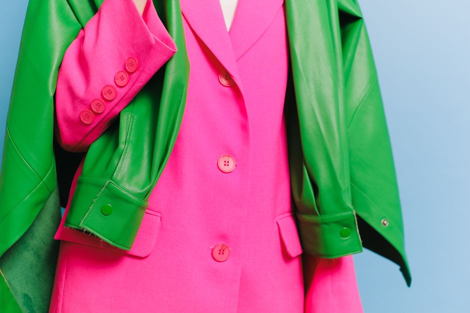 Pessoa usando combinação vibrante de blazer verde e vestido rosa, simbolizando criatividade e estilo moderno.