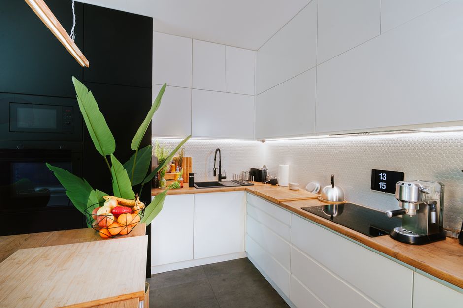 Cozinha moderna com design minimalista, destaque para iluminação embutida e utensílios de inox.