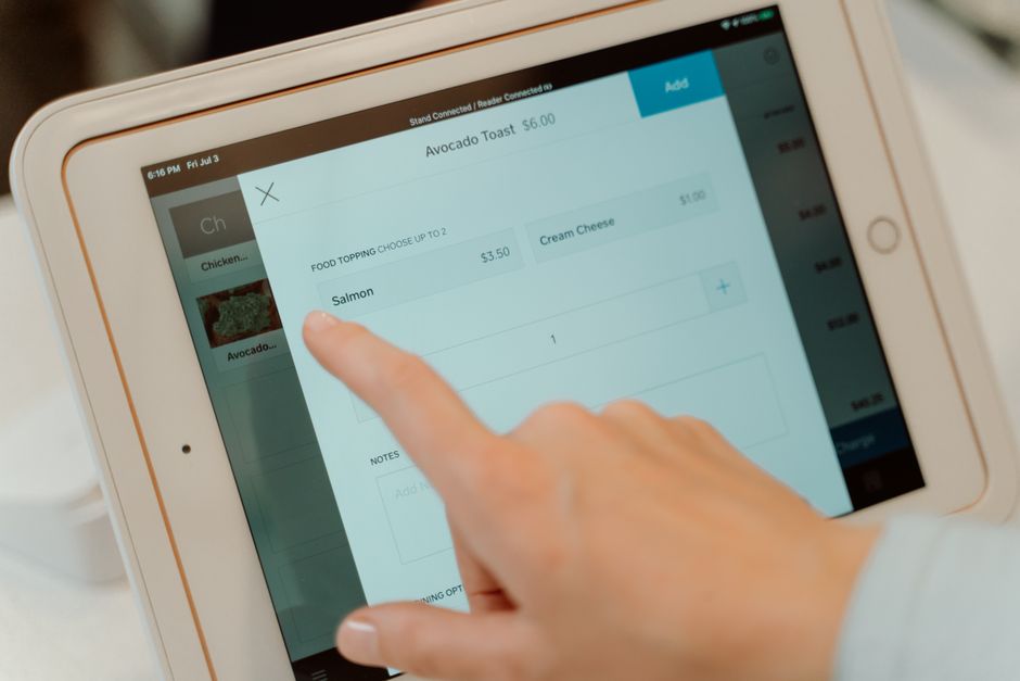 Pessoa usando um tablet para fazer um pedido de comida, evidenciando tecnologia e alimentação.