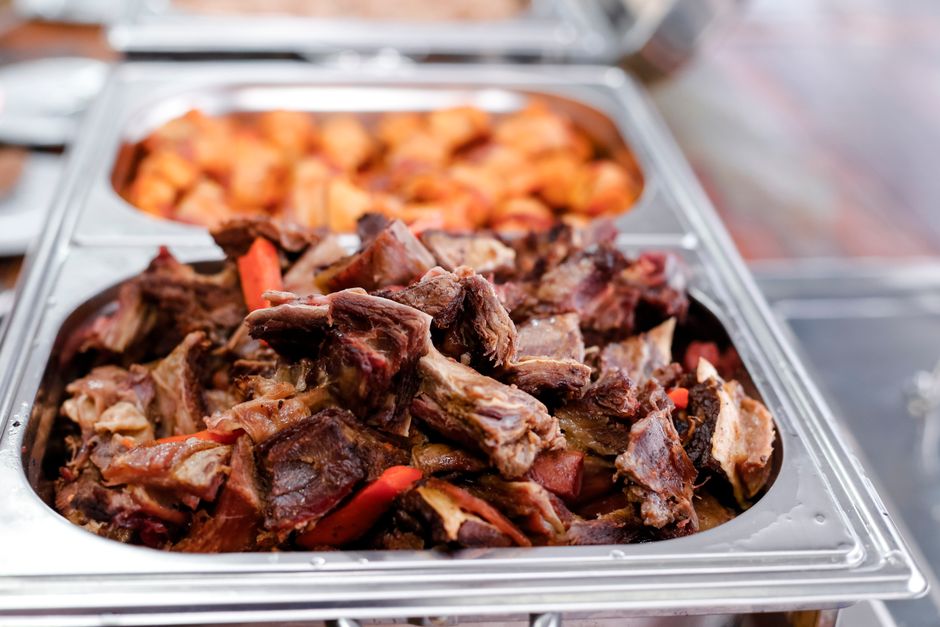 Imagem de uma bandeja de alimentos com carne assada e acompanhamentos, comum em buffet ou churrascaria.