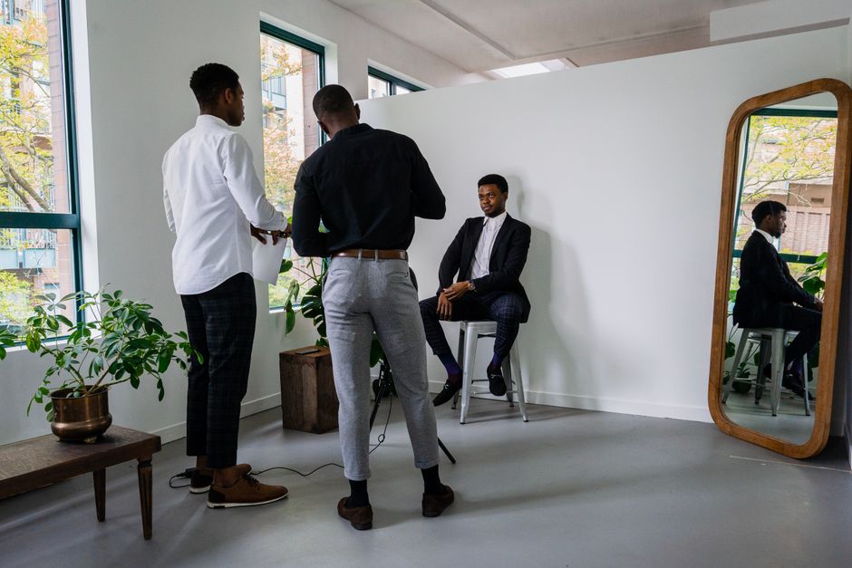 Homens em uma sessão de fotos para um perfil profissional, com fundo clean e iluminação natural, refletindo um ambiente corporativo moderno.
