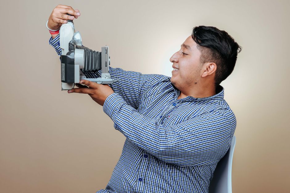 Homem sorridente segurando uma câmera antiga, representando criatividade e fotografia.