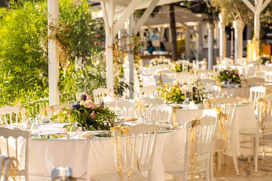 Foto de uma cerimônia ao ar livre com mesas decoradas, evidenciando um ambiente de evento elegante e festivo na natureza