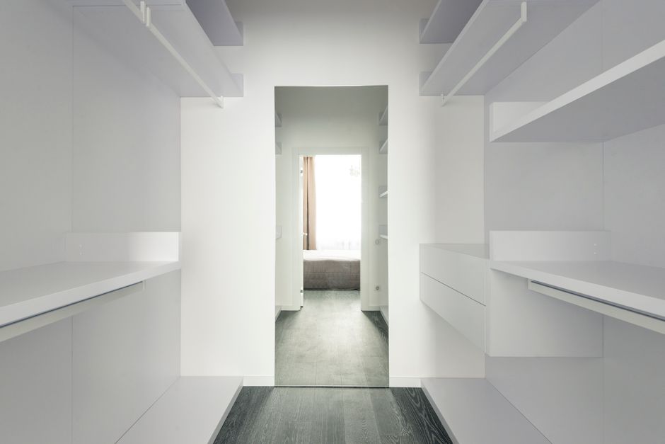 Imagem de um closet ou armário desocupado e bem iluminado, com paredes brancas e prateleiras embutidas, sugerindo organização e espaço para armazenamento pessoal ou empresarial.